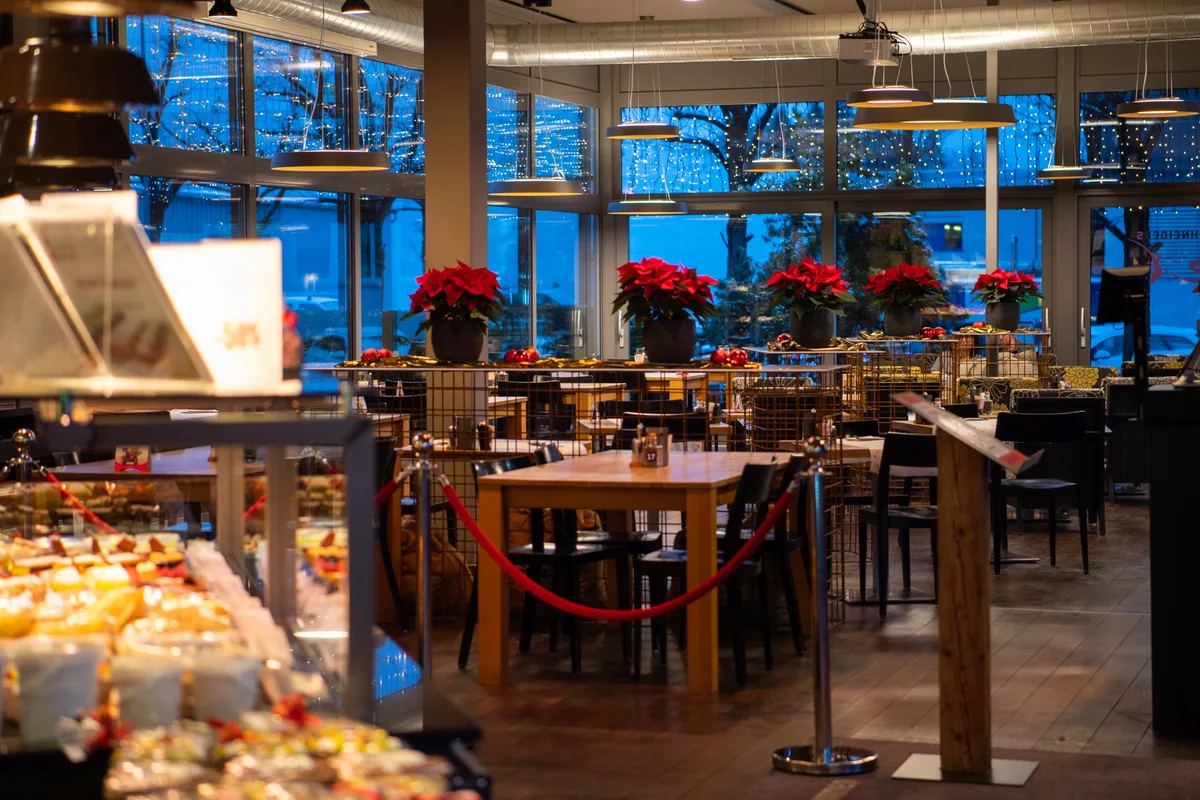 Innovatives Konzept: «Schneiders Quer» war Confiserie, Bäckerei, Pizzeria, Café, Lounge und Hotel in einem. (Archiv) Innenansicht von «Schneiders Quer» in Pfäffikon. Man sieht Tische mit roten Blumen drauf und im Vordergrund eine Kühlvitrine.